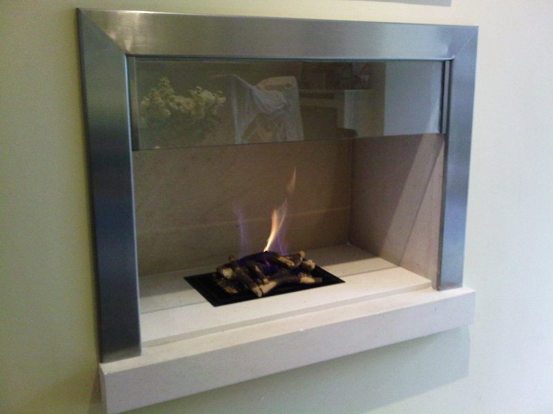 Polished steel contemporary fireplace surround in a living room with gas fire