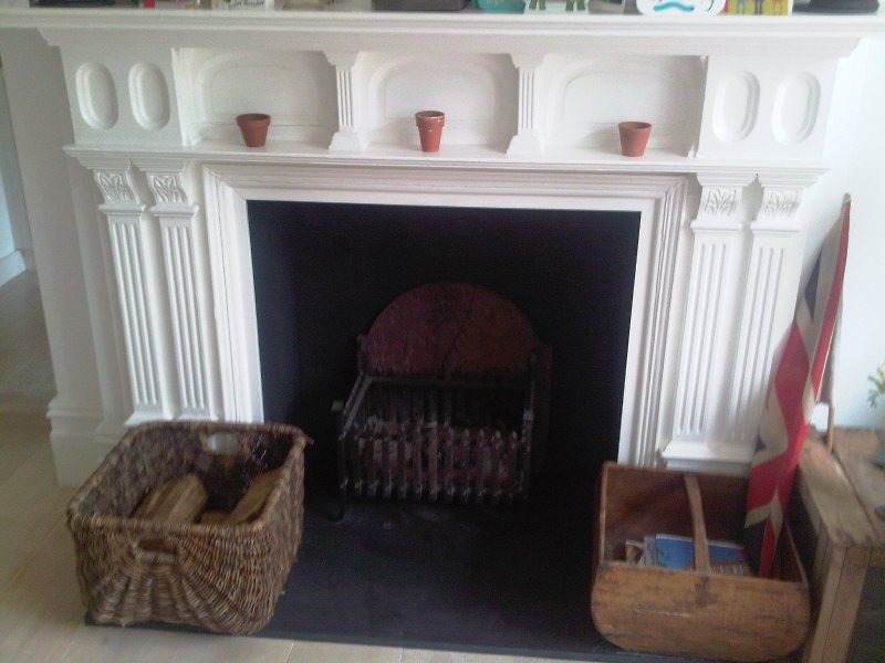 White painted wooden fireplace mantle surround with log basket